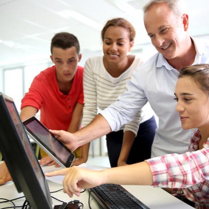 A group of people looking at a tablet and computer screen together